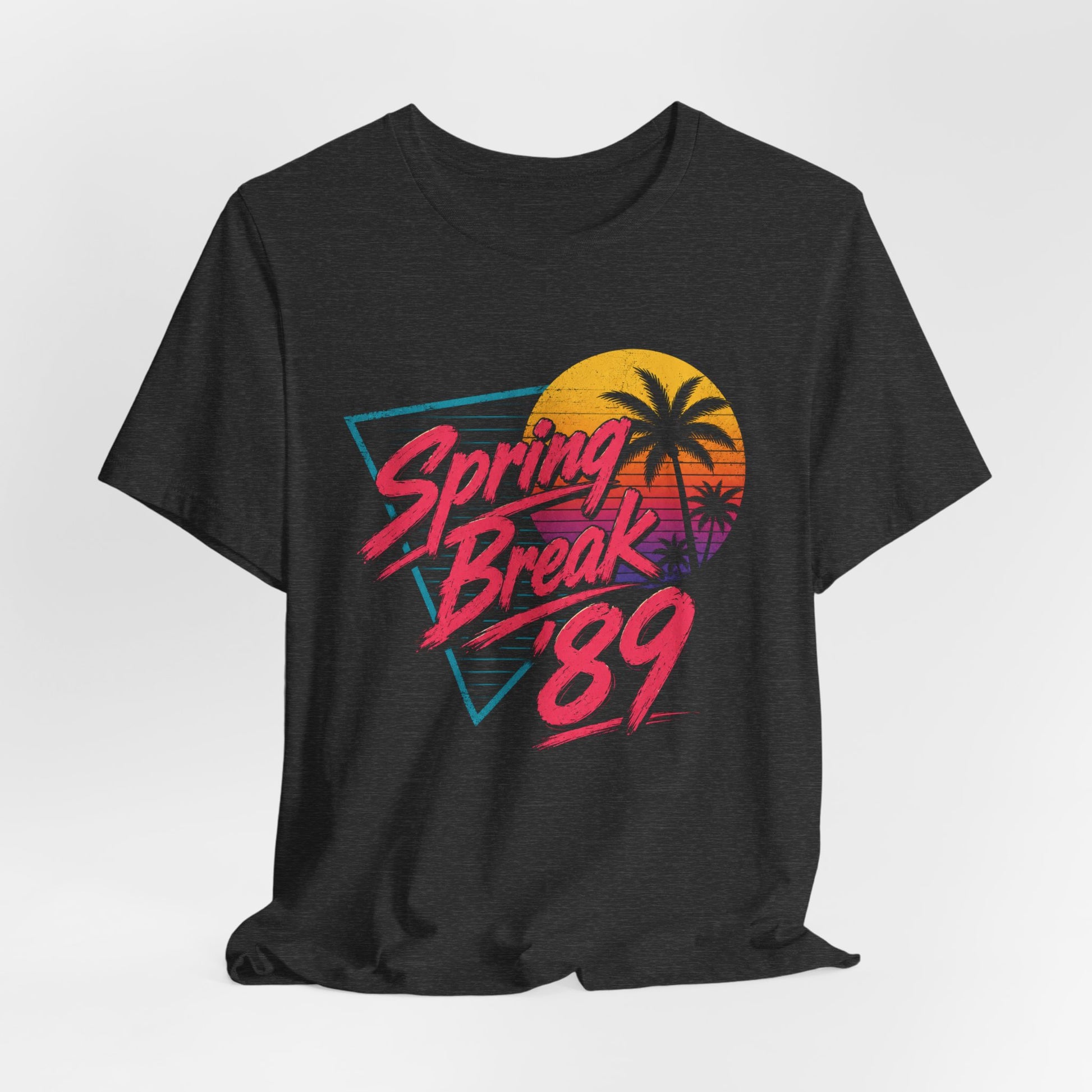 A gray heather crewneck t-shirt featuring a retro graphic with the text 'Spring Break '89' in pink, layered over a sunset and palm tree design.