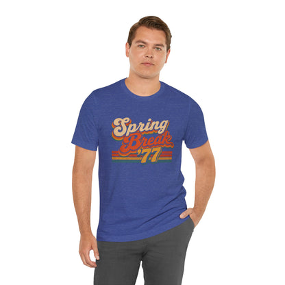 A man wearing a heather blue t-shirt with a retro-style 'Spring Break '77' graphic on the chest.