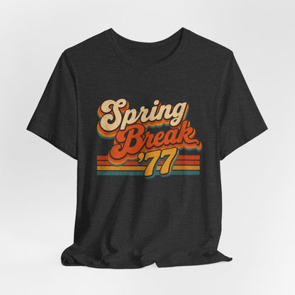 A  heather gray t-shirt featuring a retro-style 'Spring Break '77' graphic print in orange, yellow, and beige tones.