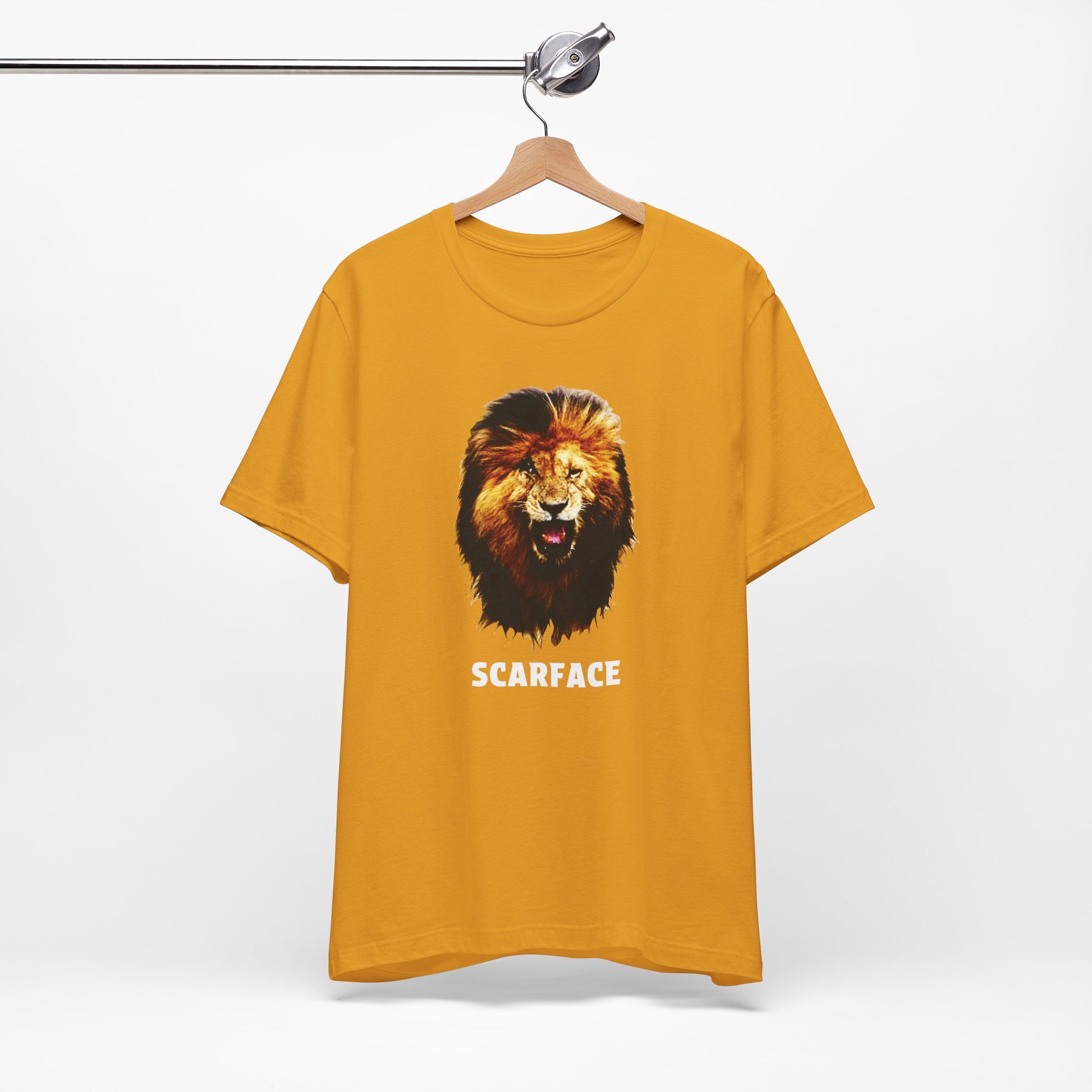 A mustard short-sleeve t-shirt featuring a graphic of a roaring lion's head with the word 'SCARFACE' printed in white below it.