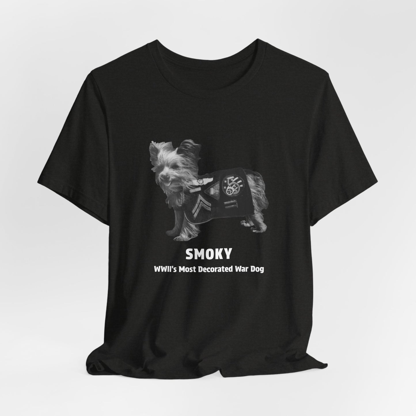 A black short-sleeve crewneck t-shirt featuring a grayscale graphic of a small dog wearing a decorated military-style jacket, with the text 'SMOKY WWII'S Most Decorated War Dog' printed below.