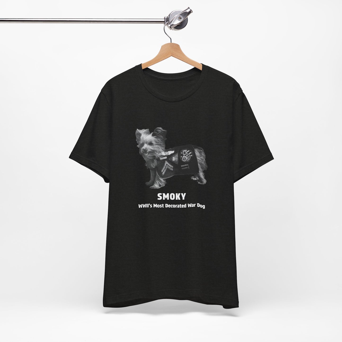 A black short-sleeve t- shirt features a grayscale graphic of a dog wearing a military combat coat with the text 'SMOKY' and 'WII'S MOST Decorated War Dog' printed below.