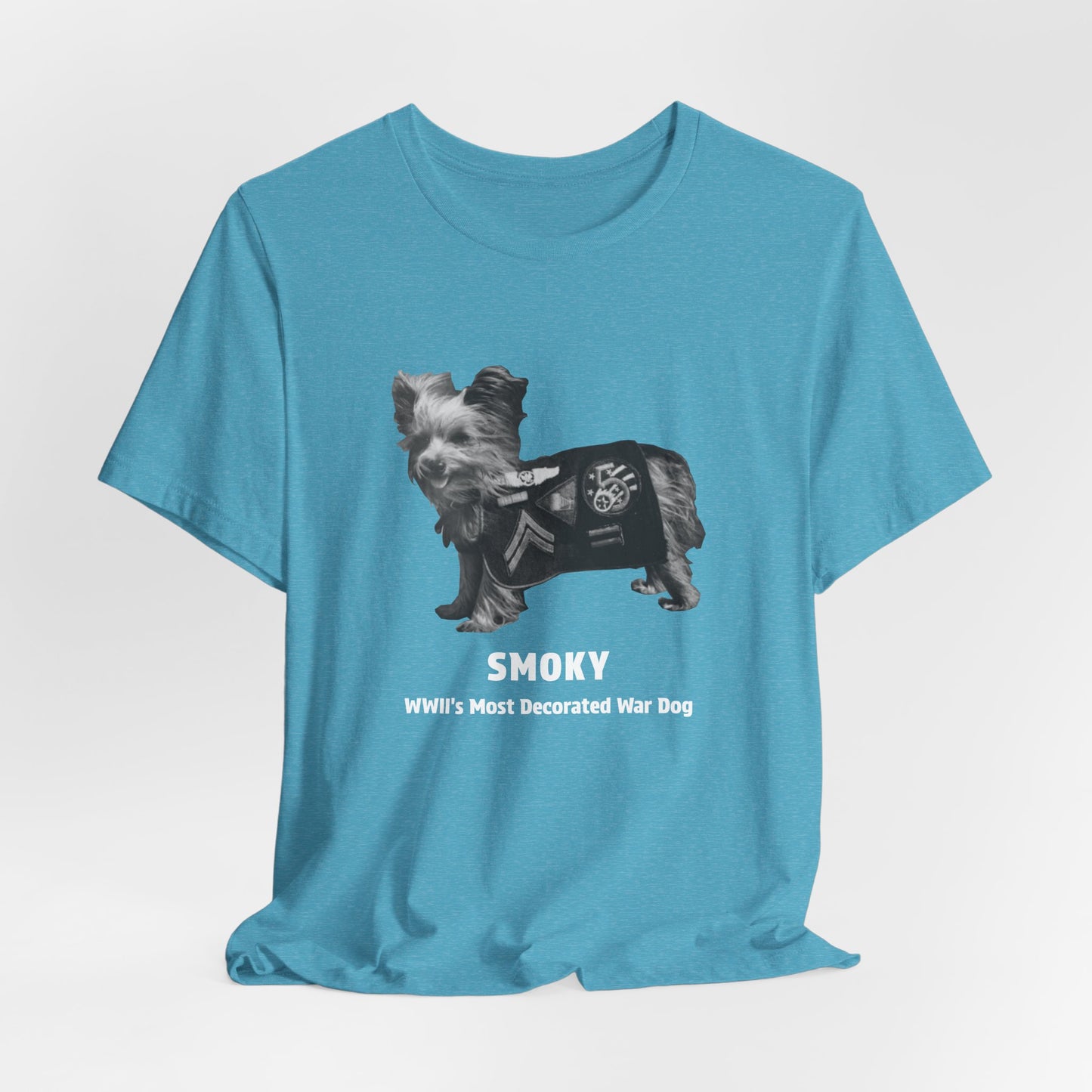 A heatheraqua short-sleeve t-shirt with a black and white graphic of a small dog wearing a military campaign patch, with the text 'SMOKY' and 'Wll's Most Decorated War Dog' printed below.
