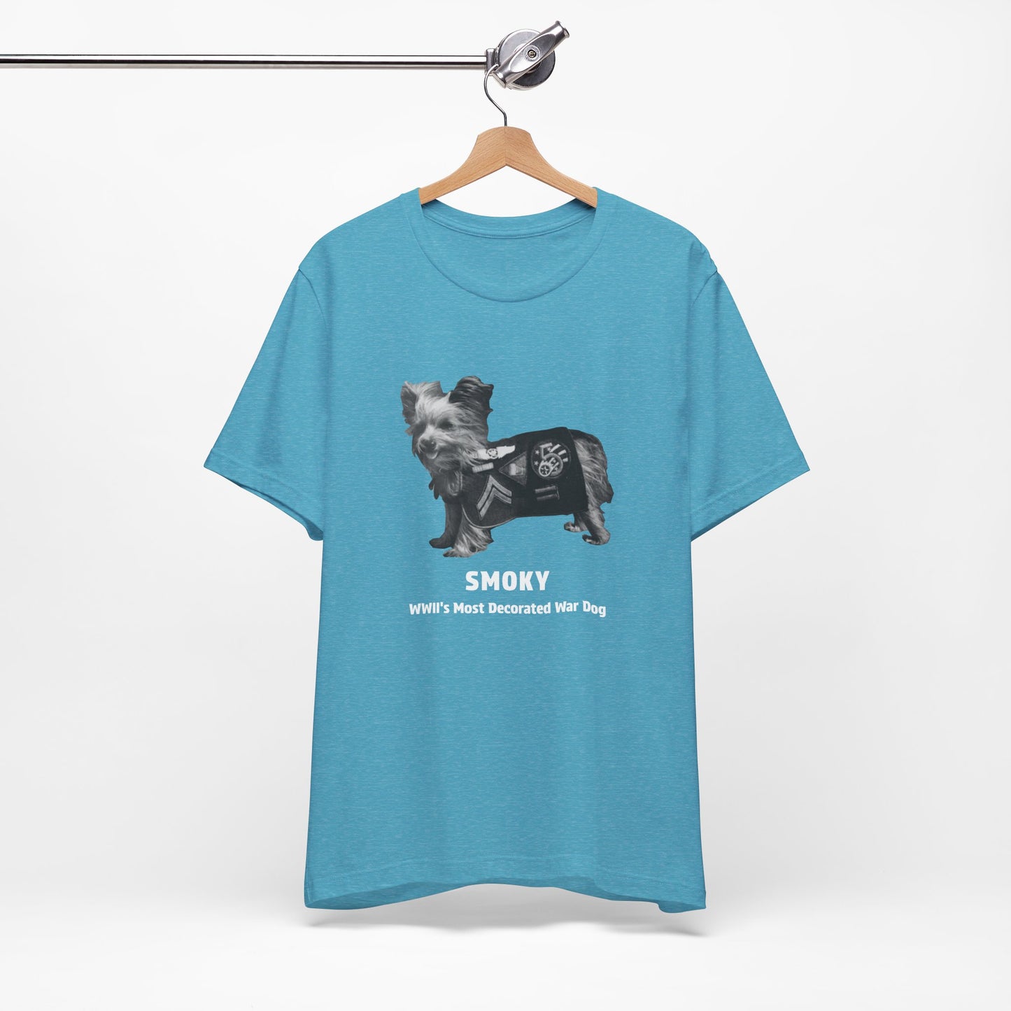 A heather aqua short-sleeve t-shirt featuring a graphic of a dog wearing a military coat with the text 'SMOKY WII'S MOST DECORATED WAR DOG' printed on the front.