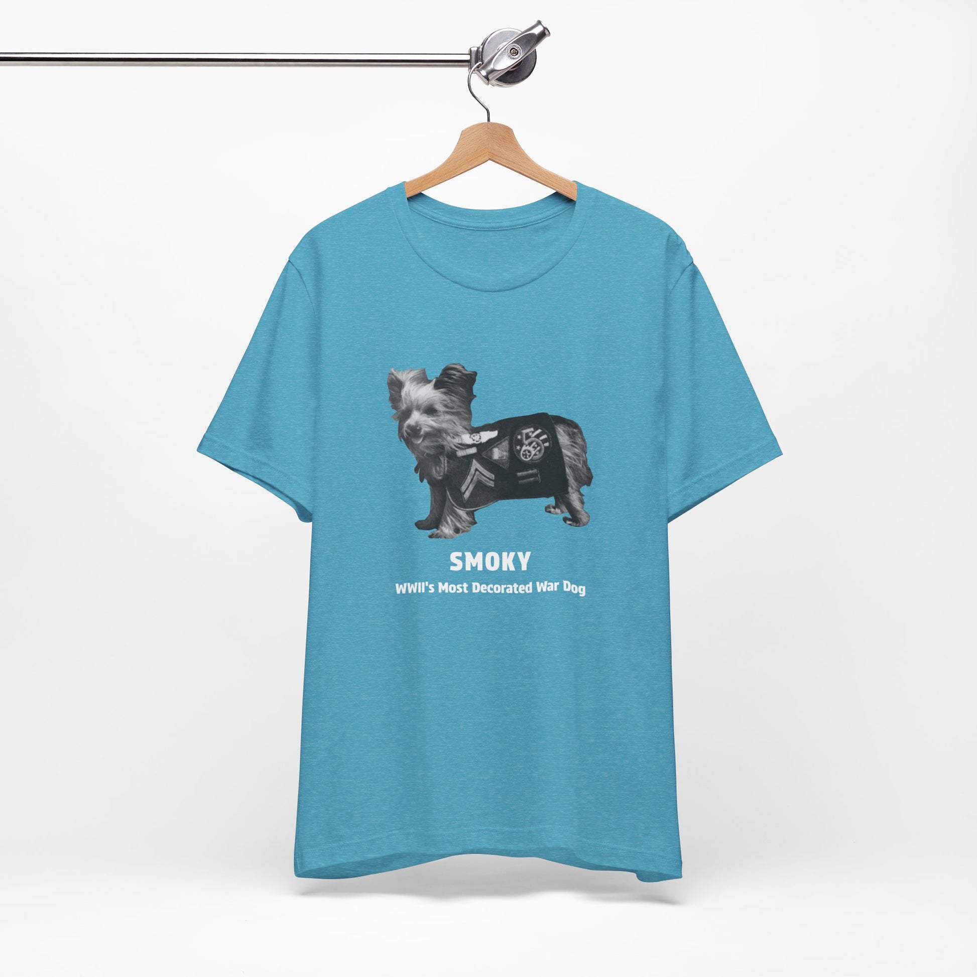 A heather aqua short-sleeve t-shirt featuring a graphic of a dog wearing a military coat with the text 'SMOKY WII'S MOST DECORATED WAR DOG' printed on the front.
