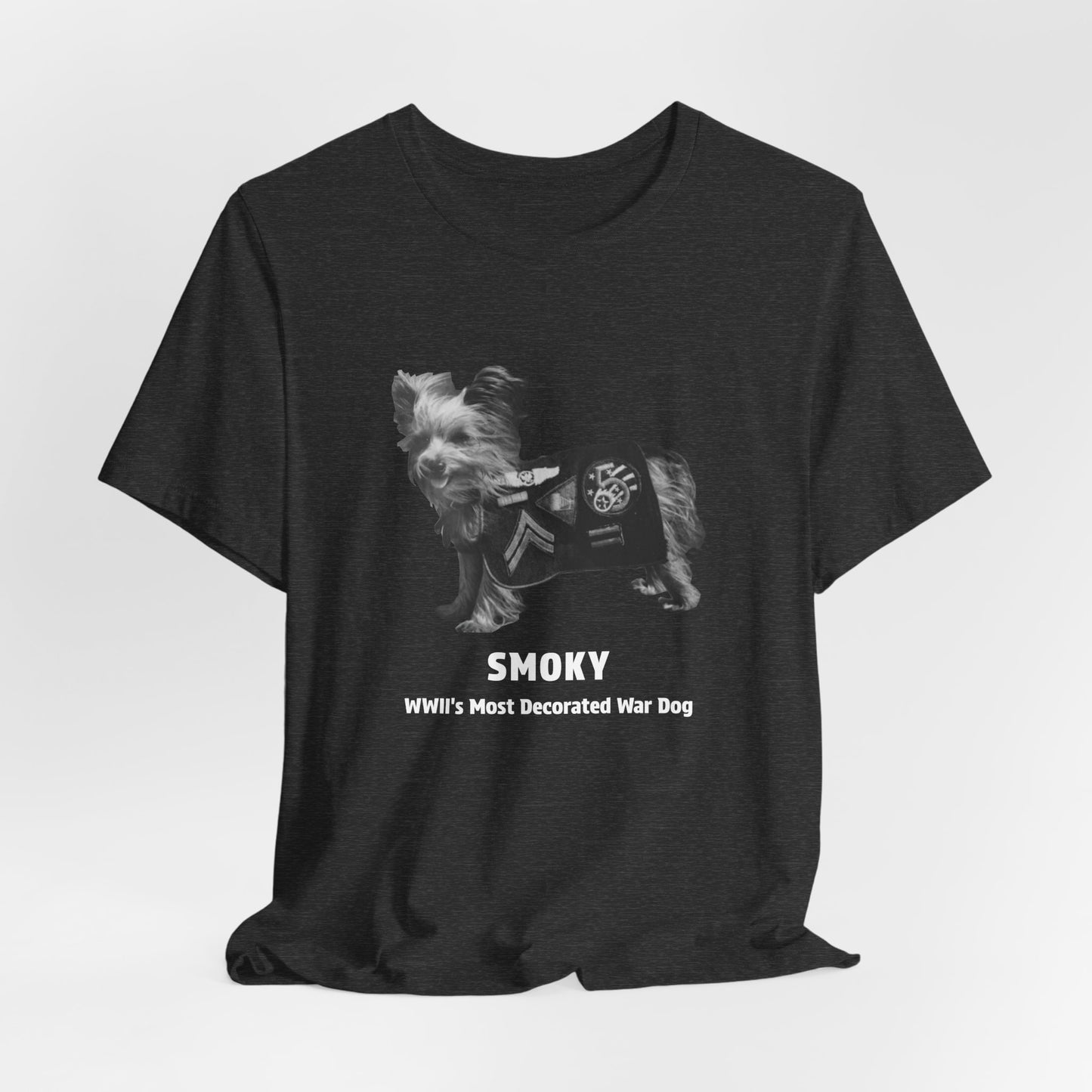 A heather gray short-sleeve crewneck t-shirt featuring a grayscale graphic of a small dog wearing a decorated military-style jacket, with the text 'SMOKY WWII'S Most Decorated War Dog' printed below.