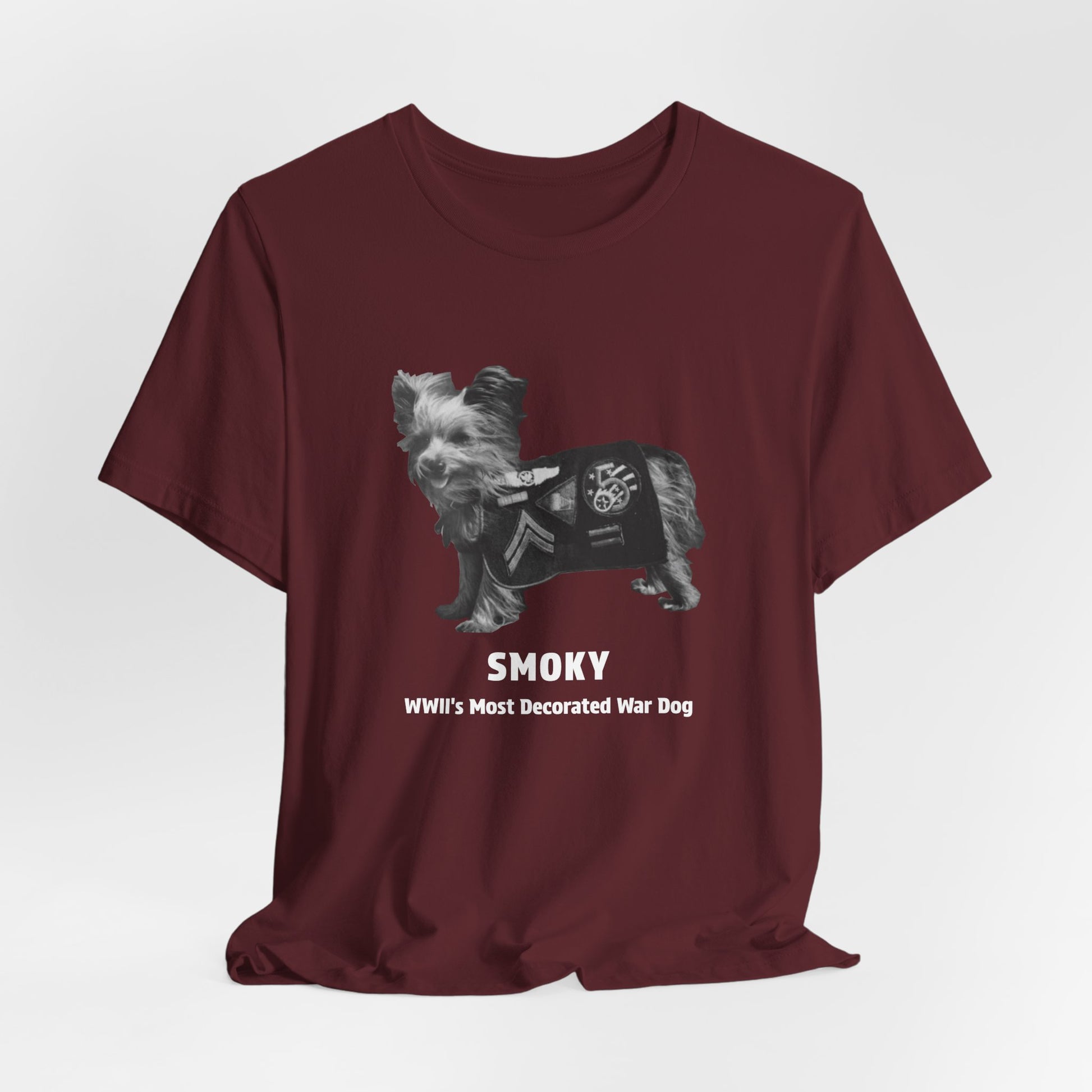A maroon short-sleeve t-shirt with a graphic of a small dog and the text 'SMOKY WWII'S Most Decorated War Dog' printed on the front.