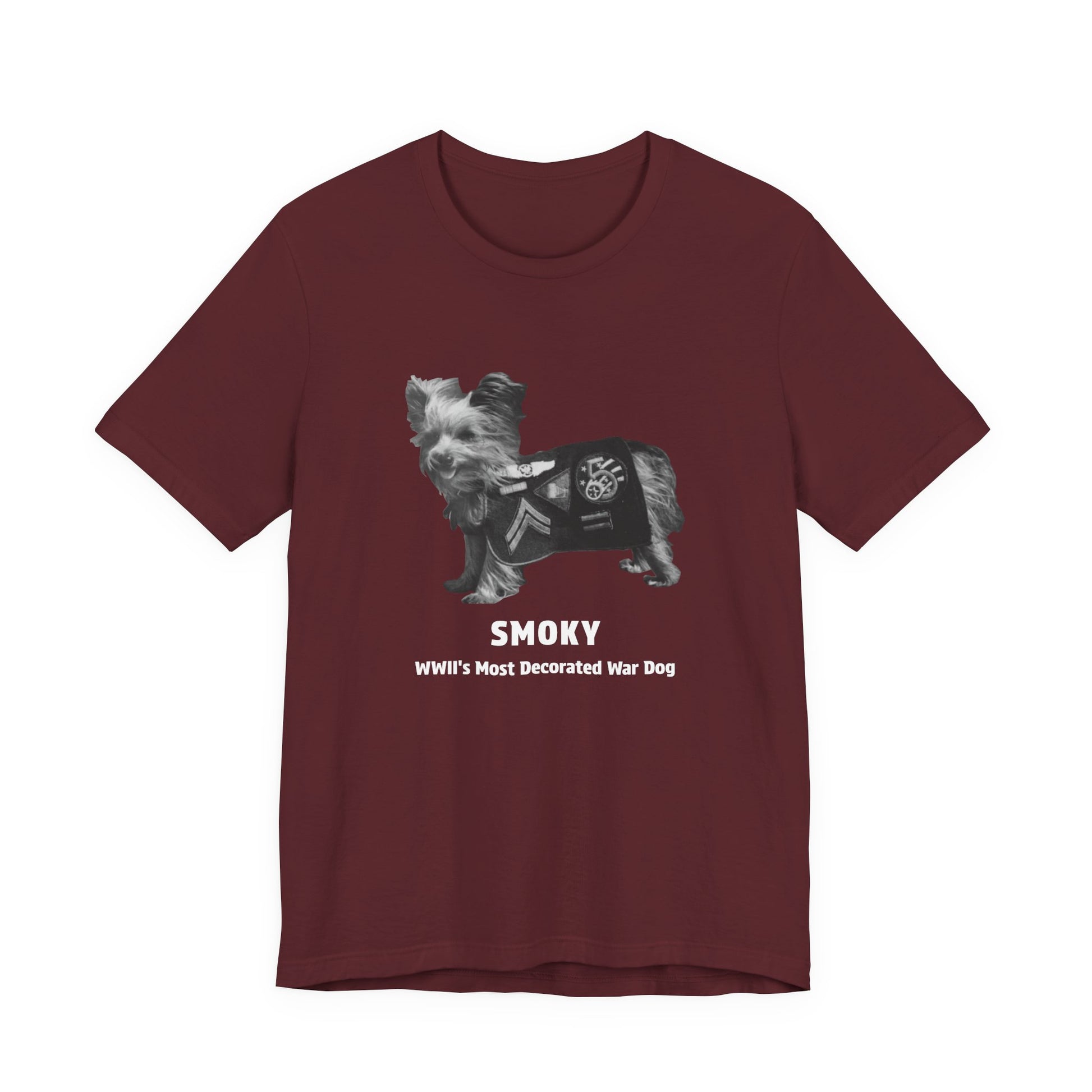 A maroon short-sleeve crewneck t-shirt featuring a graphic of a small dog wearing a military combat utility vest, with the text 'SMOKY' and 'WWII'S Most Decorated War Dog' printed below.