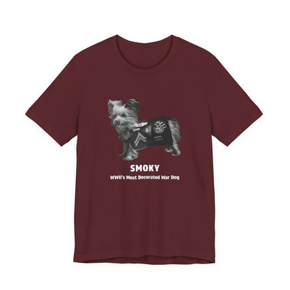 A maroon short-sleeve crewneck t-shirt featuring a graphic of a small dog wearing a military combat utility vest, with the text 'SMOKY' and 'WWII'S Most Decorated War Dog' printed below.